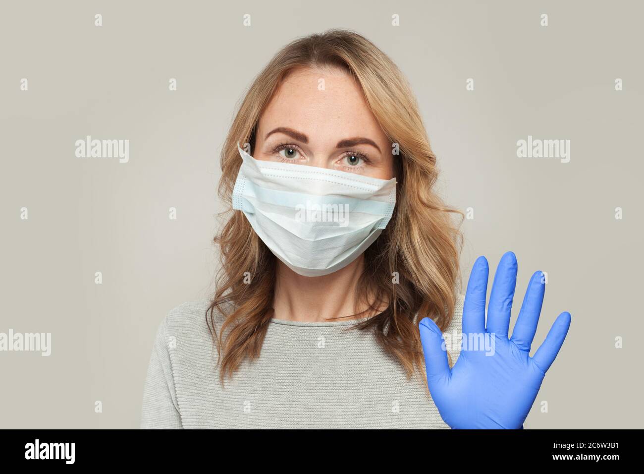 Mature woman in medical protective face mask showing stop gesture on ...