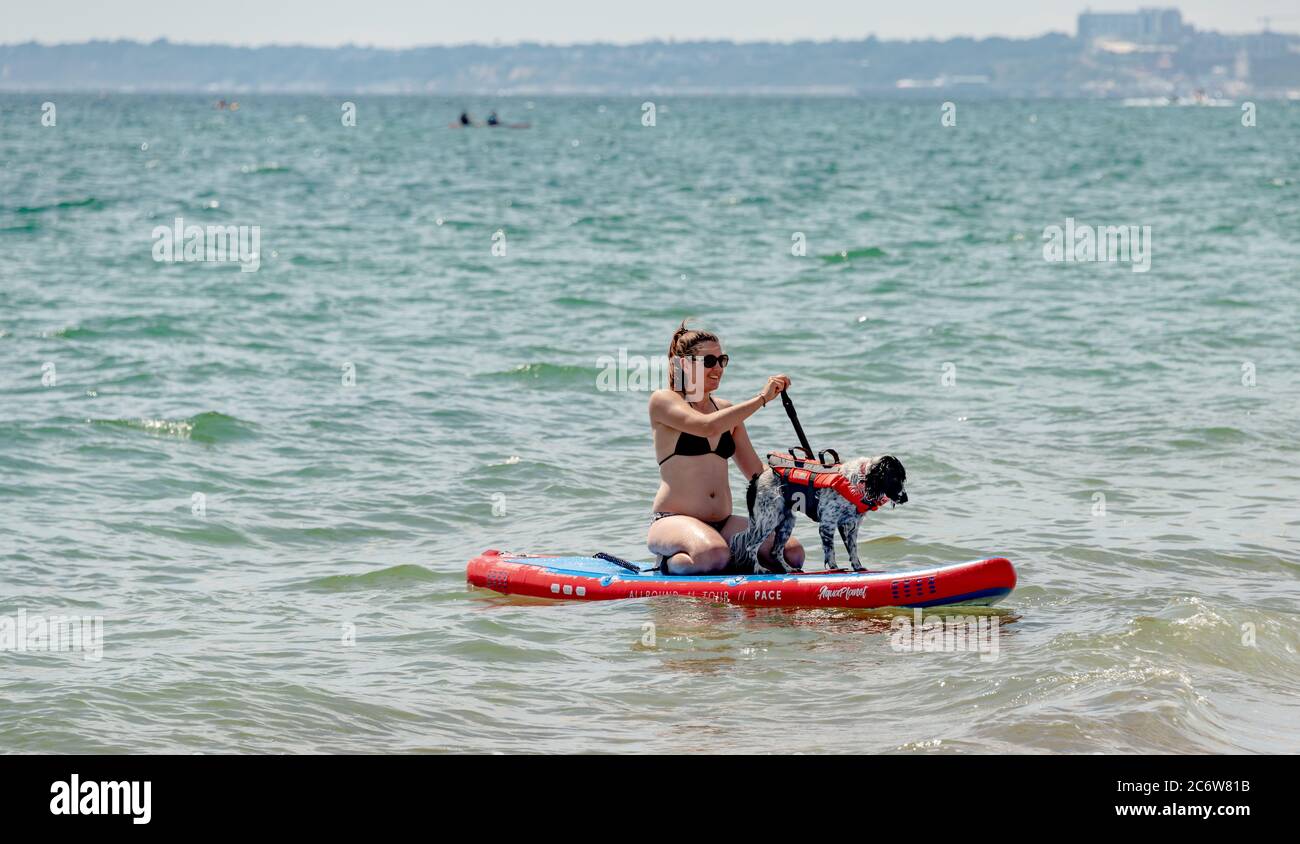 Christchurch, UK. Sunday 7 July 2020. A young woman on a paddleboard with her dog. Credit: Thomas Faull/Alamy Live News Stock Photo