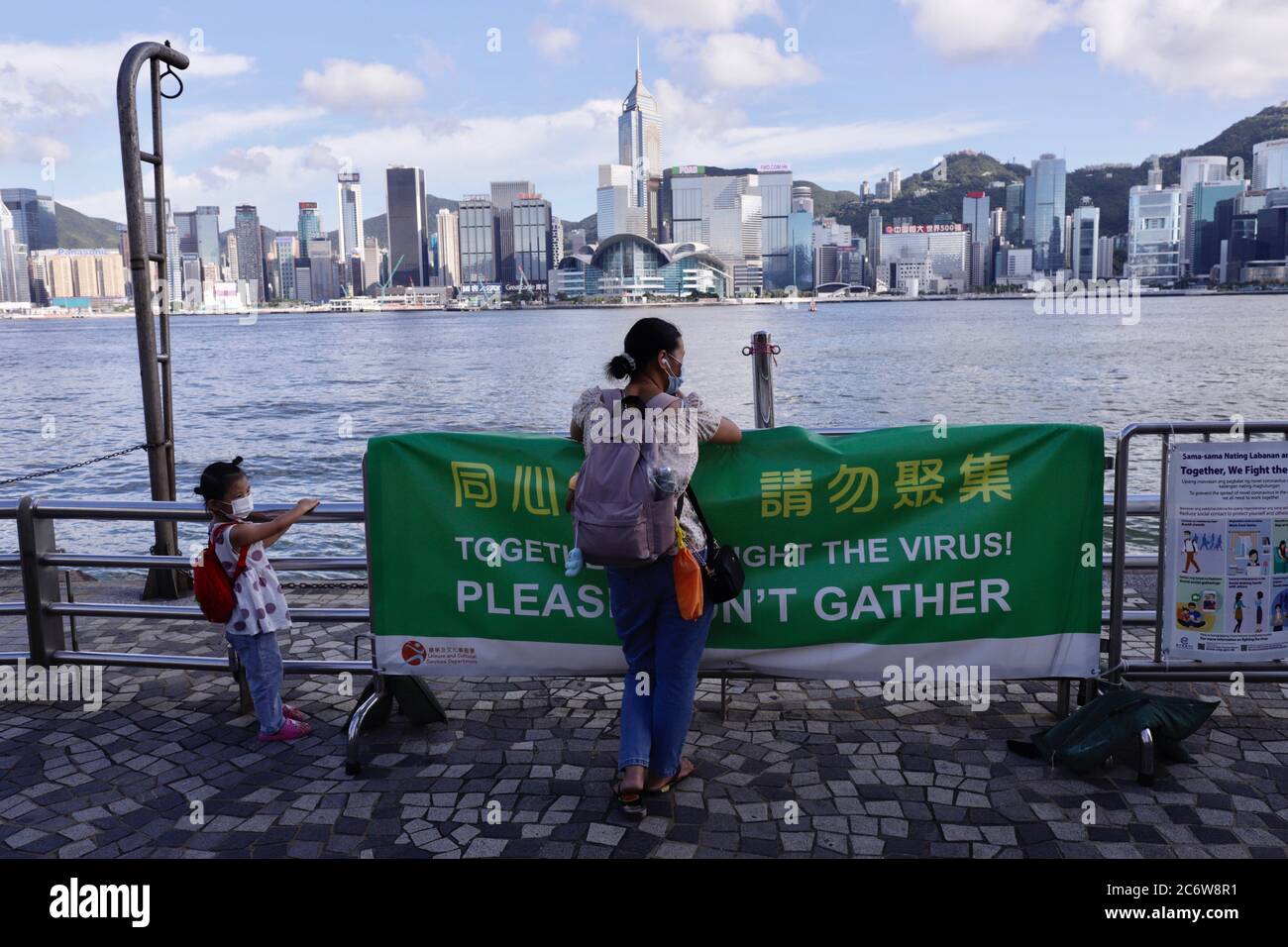 Hong Kong, CHINA. 12th July, 2020. Mother and baby daughter watching the harbour view at Victoria Harbour waterfront in the late afternoon. Hong Kong is hit by third wave of coronavirus attack. Sudden rise of certified infection cases have alerted the government to issue a warning to the citizens to obey the rule of social distancing and encouraging people to stay home as much as possible to avoid unnecessary contacts in the public places.July-12, 2020 Hong Kong.ZUMA/Liau Chung-ren Credit: Liau Chung-ren/ZUMA Wire/Alamy Live News Stock Photo