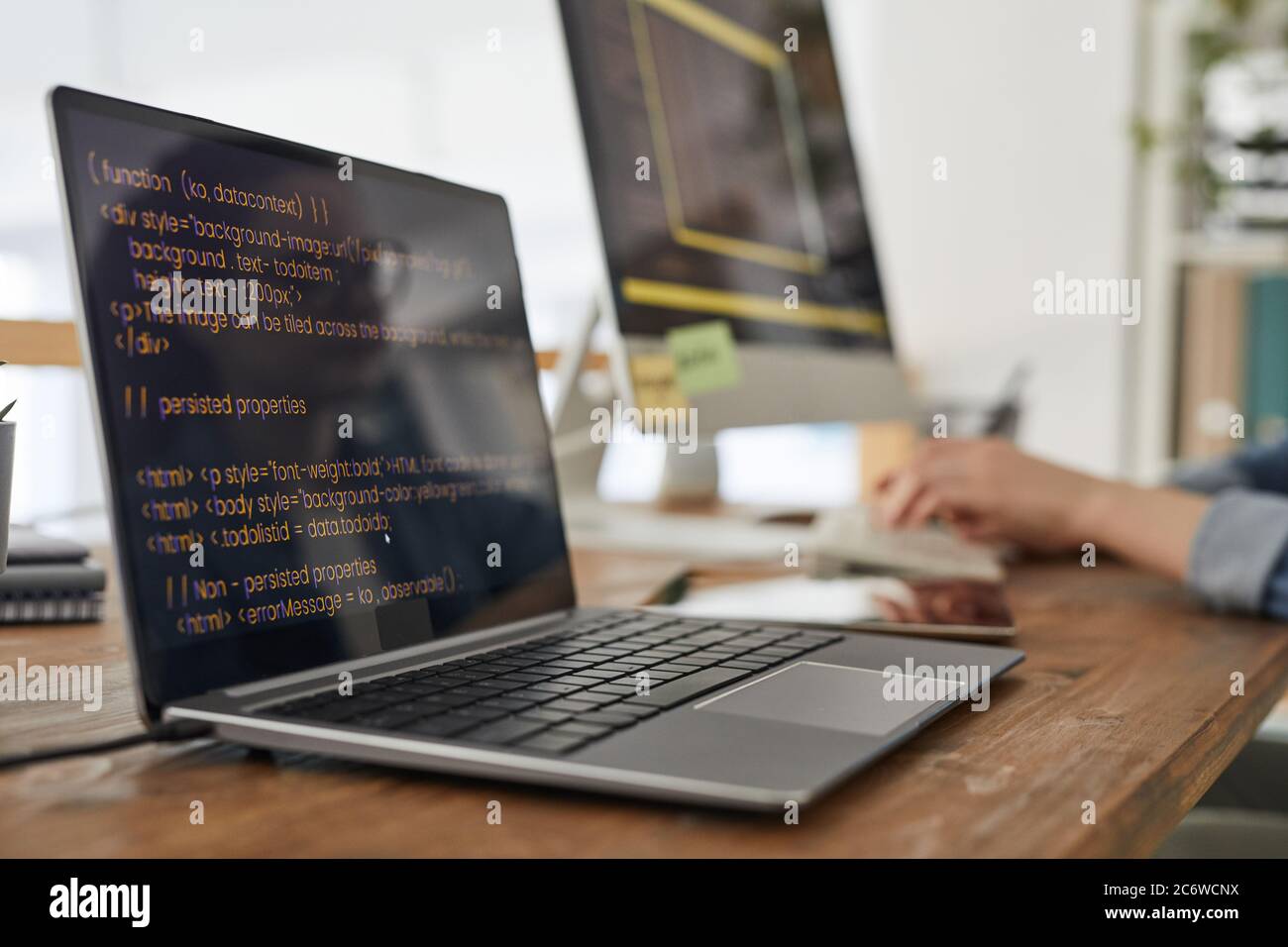 Close up of two computers with programming code on screen in minimal ...