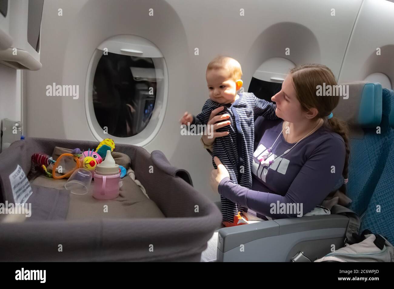 Infant plays on mother hands at the airplane. Interest to special baby  bassinet during the flight Stock Photo - Alamy