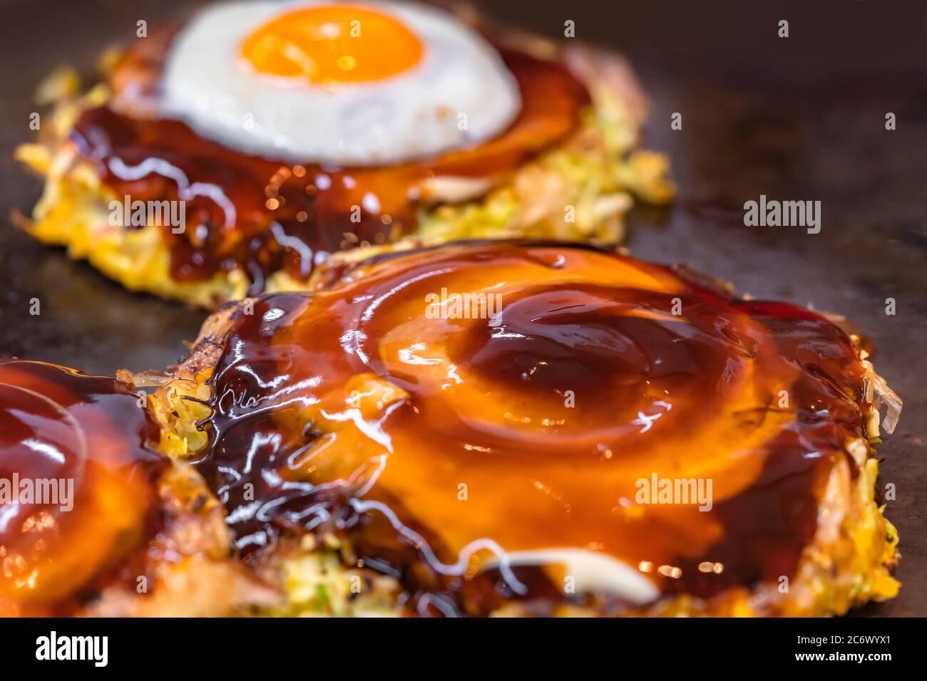 Closeup on a fried egg and an okonomiyaki Japanese omelet prepared