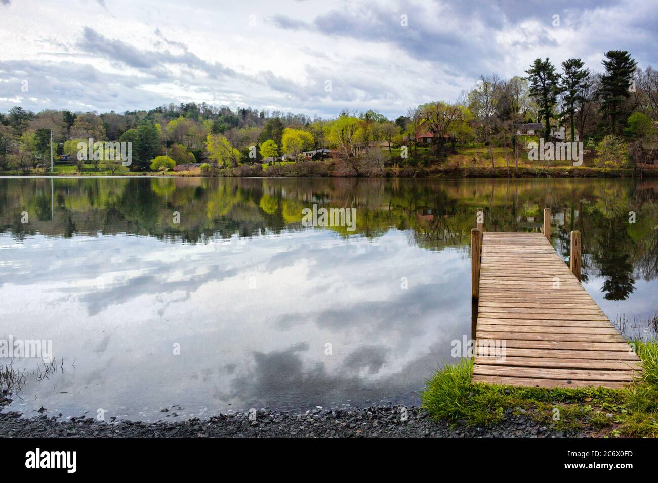 A dock juts into Beaver Lake, with a view of reflections of houses and