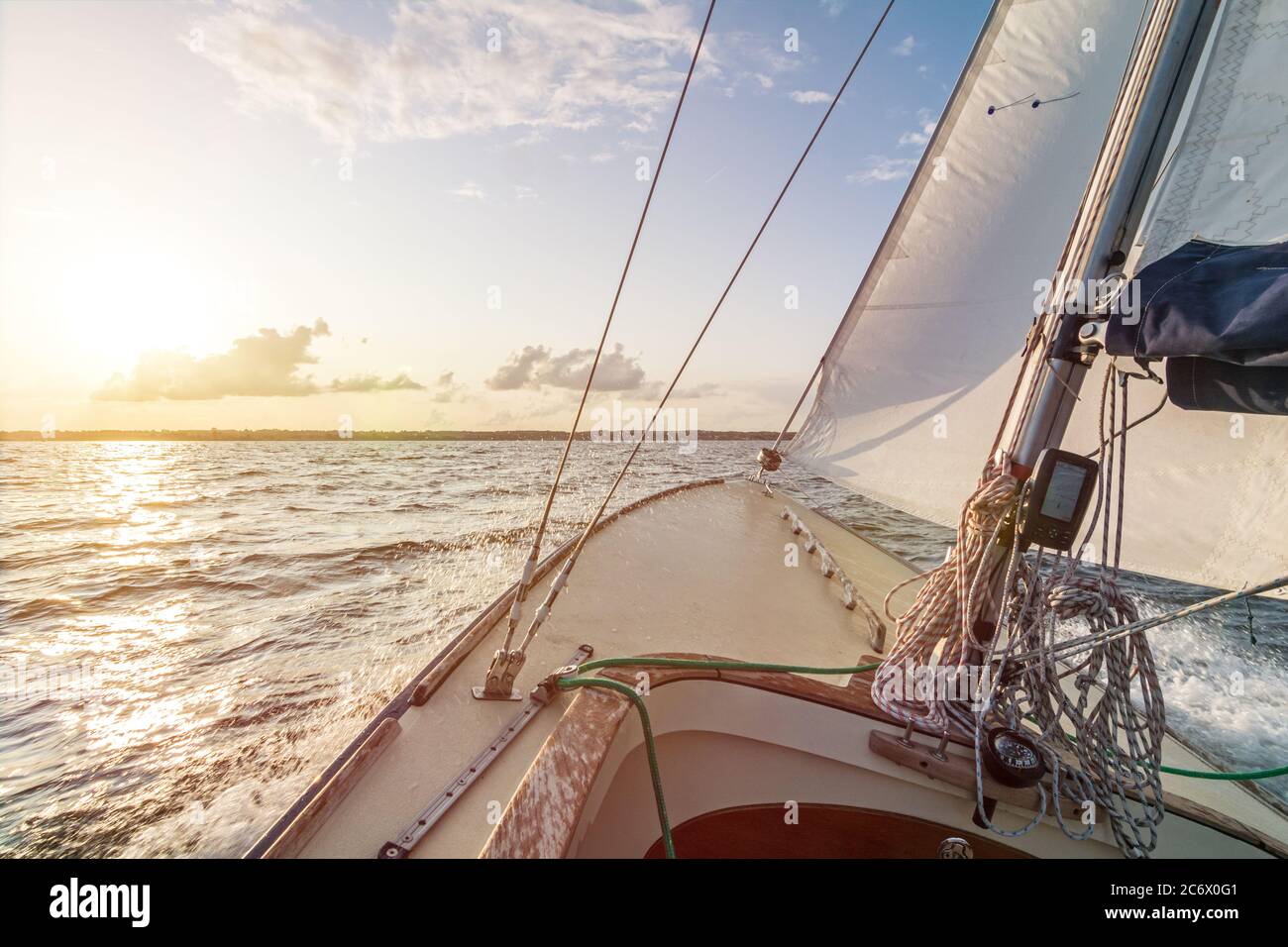 Sailing boat sailing fast into the beautiful sunset during choppy sea Stock Photo