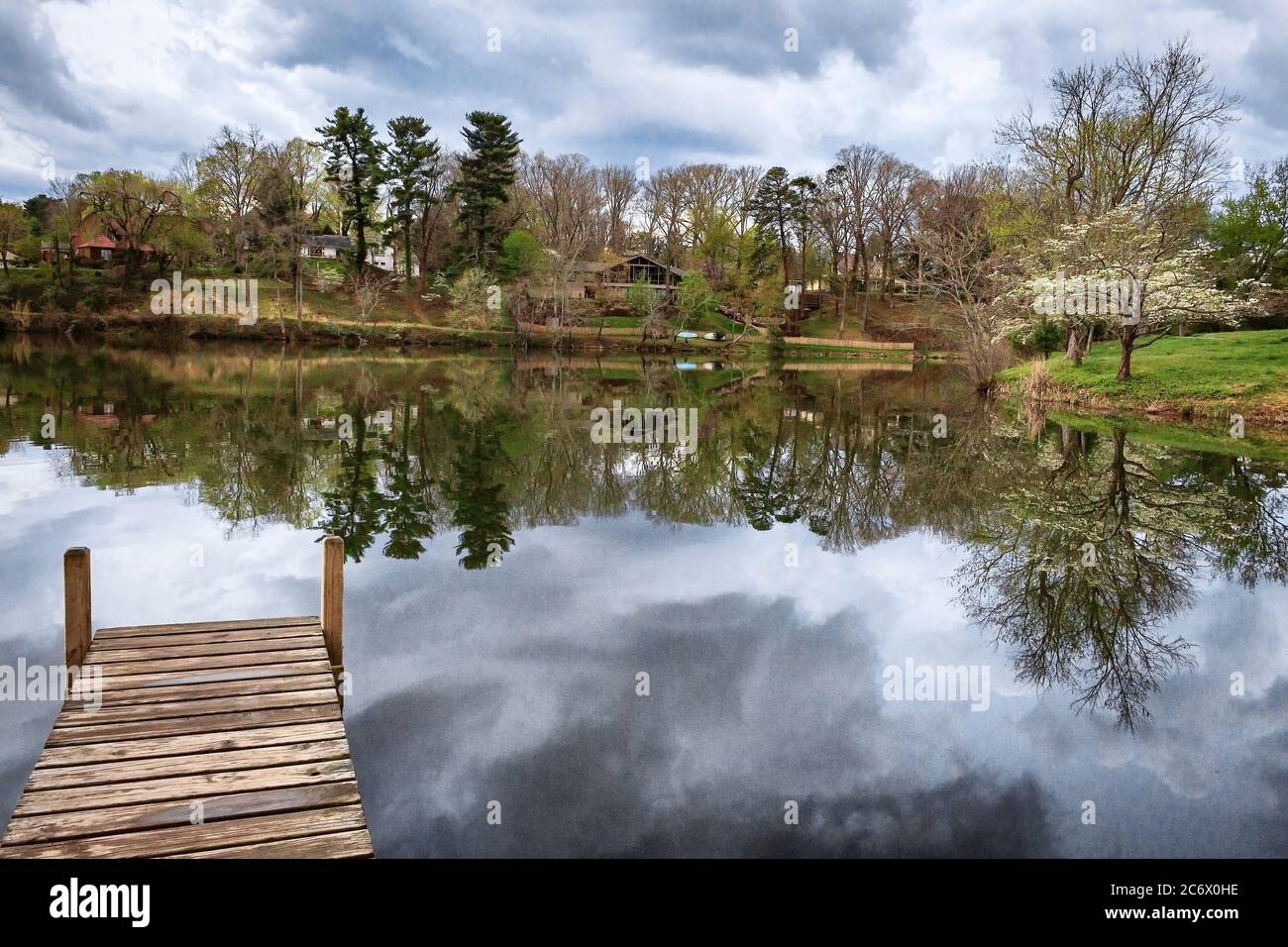 A dock juts into Beaver Lake, with a view of reflections of houses and
