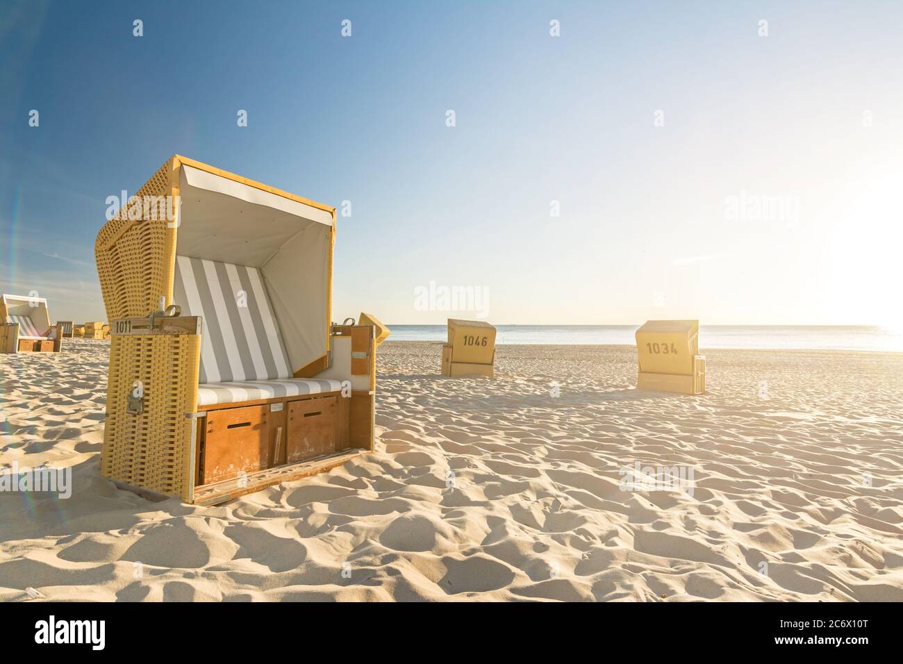 Beach chairs at the ocean with scenic lens flare during the sunset on the island of Sylt in Germany Stock Photo