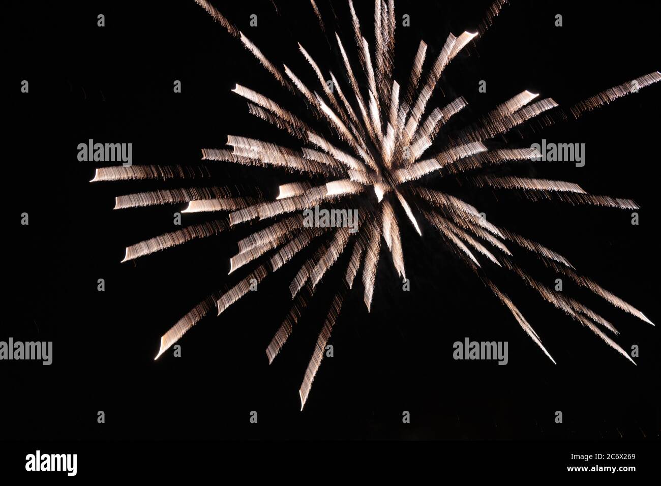 close up of a single burst of a crysanthemum rocket fireworks explosion glowing against the night sky from a new york city rooftop Stock Photo