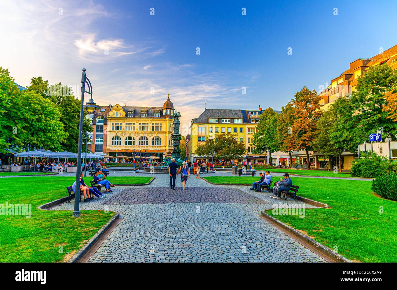 Koblenz, Germany, August 23, 2019: Gorresplatz square with old buildings, History Column fountain, green lawn and people sitting on benches in historical city centre, Rhineland-Palatinate state Stock Photo