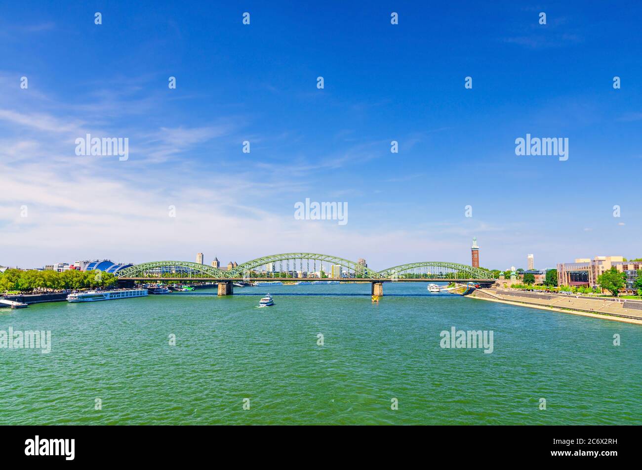 The Hohenzollern Bridge or Hohenzollernbrucke across Rhine river with cargo ships sailing on water, pedestrian and railway steel bridge, Cologne city centre, North Rhine-Westphalia, Germany Stock Photo