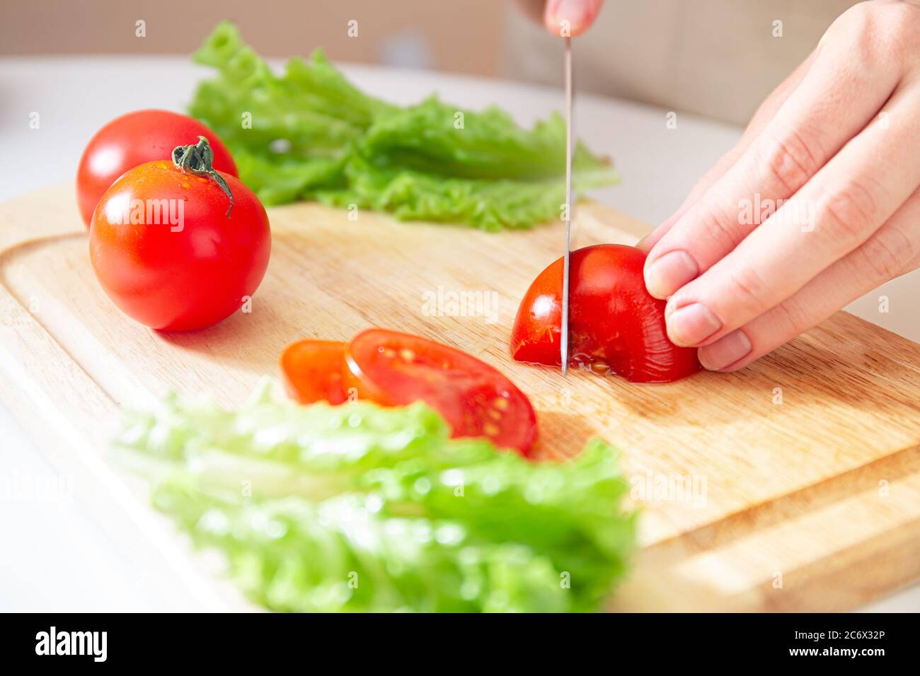 https://c8.alamy.com/comp/2C6X32P/elegant-hands-of-a-young-girl-cut-juicy-red-tomato-into-halves-on-a-wooden-cutting-board-preparation-of-ingredients-and-vegetables-organic-products-2C6X32P.jpg