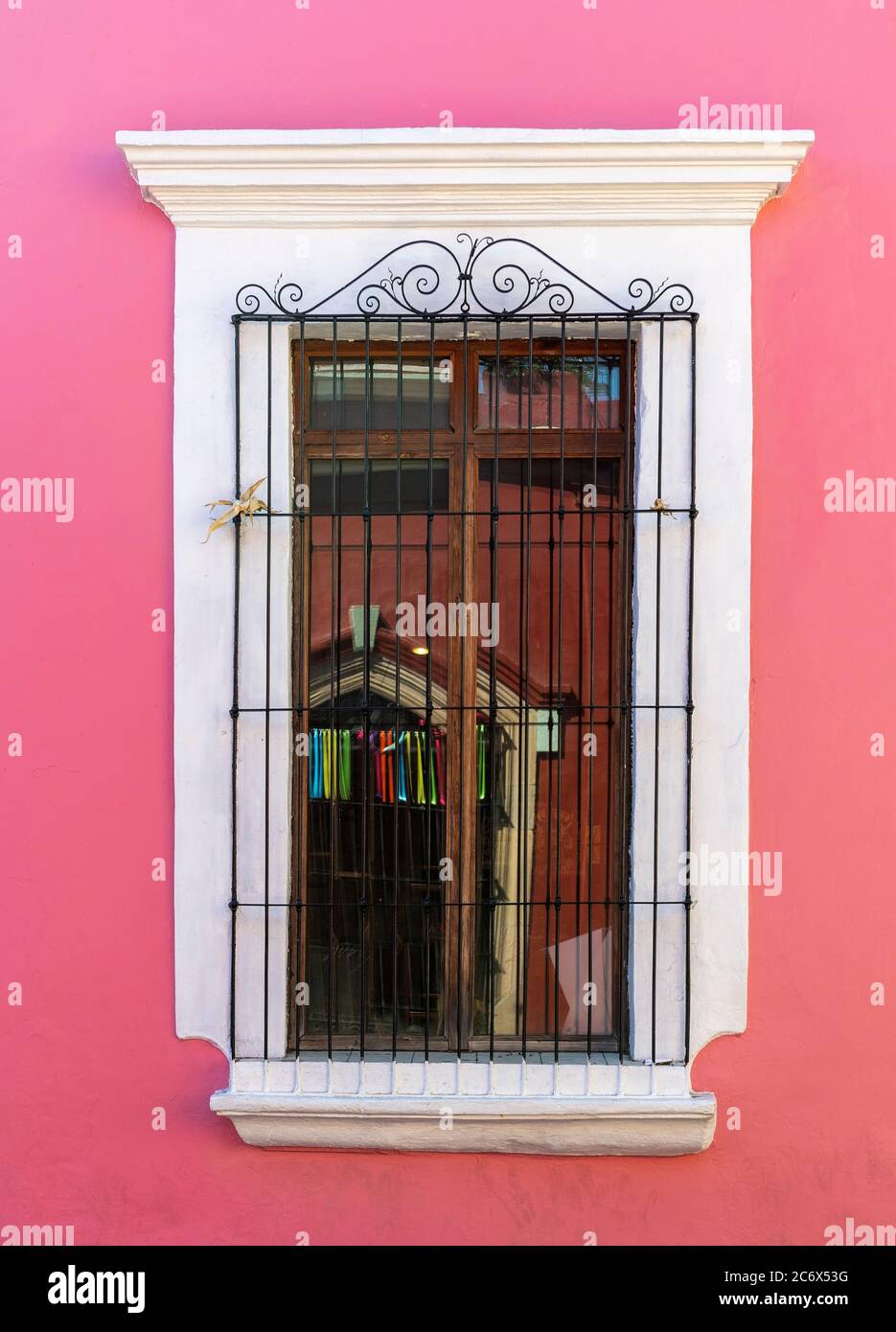 Colonial style architecture with a pink wall and wrought iron decoration on wooden window, Oaxaca, Mexico. Stock Photo