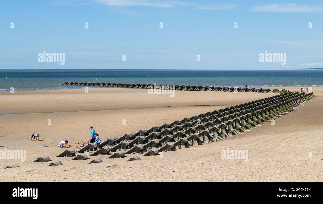 Modern sea defences on Wallasey beach seen in July 2020 (near Liverpool, England) as the tide rushes in. Stock Photo