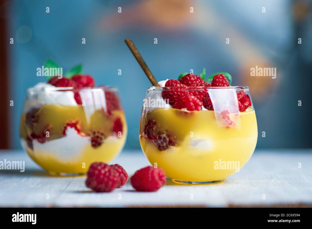 Raspberry fruit parfait with cream in a cup against blue background Stock Photo