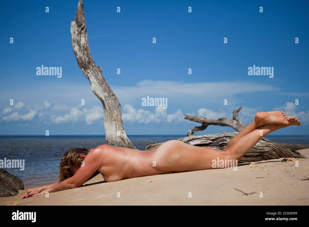 Very physically fit woman lying naked, face down on the beach Stock Photo