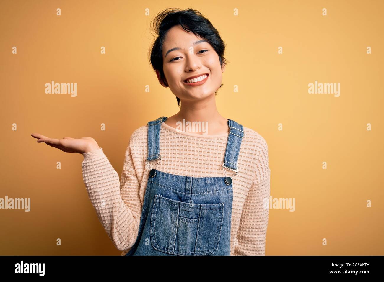 Young beautiful asian girl wearing casual denim overalls over isolated ...