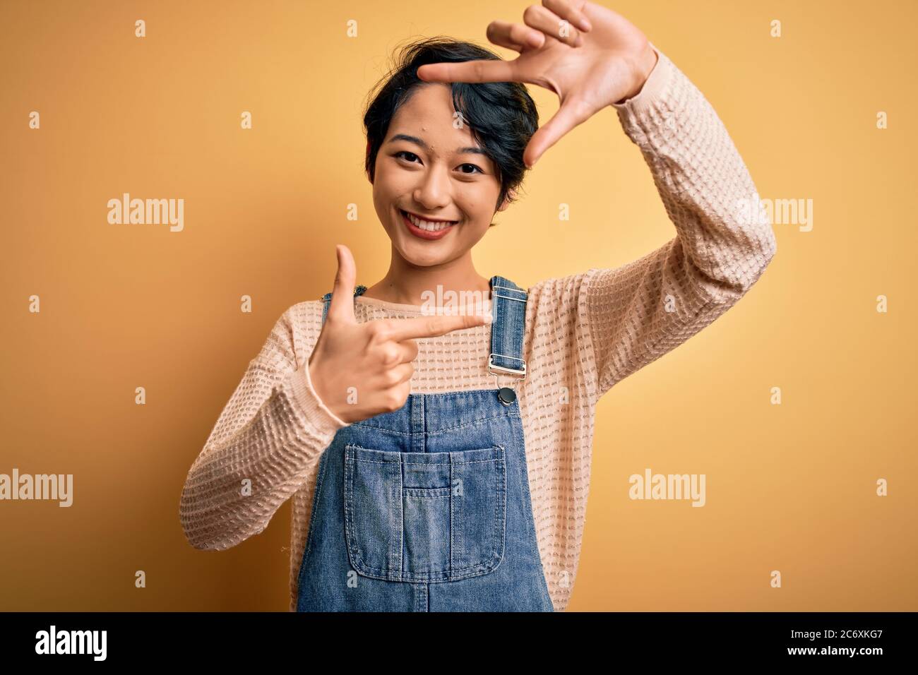 Young beautiful asian girl wearing casual denim overalls over isolated ...