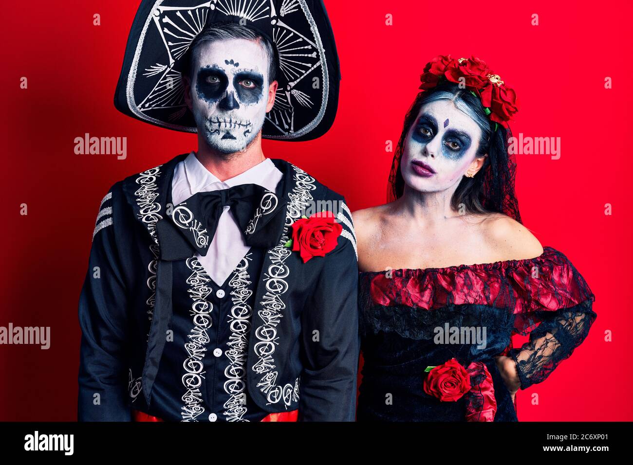 Young couple wearing mexican day of the dead costume over red depressed ...