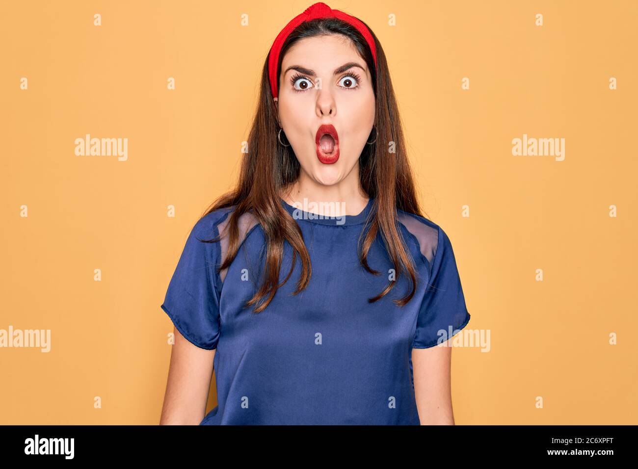 Young beautiful brunette woman wearing red lips over yellow background ...