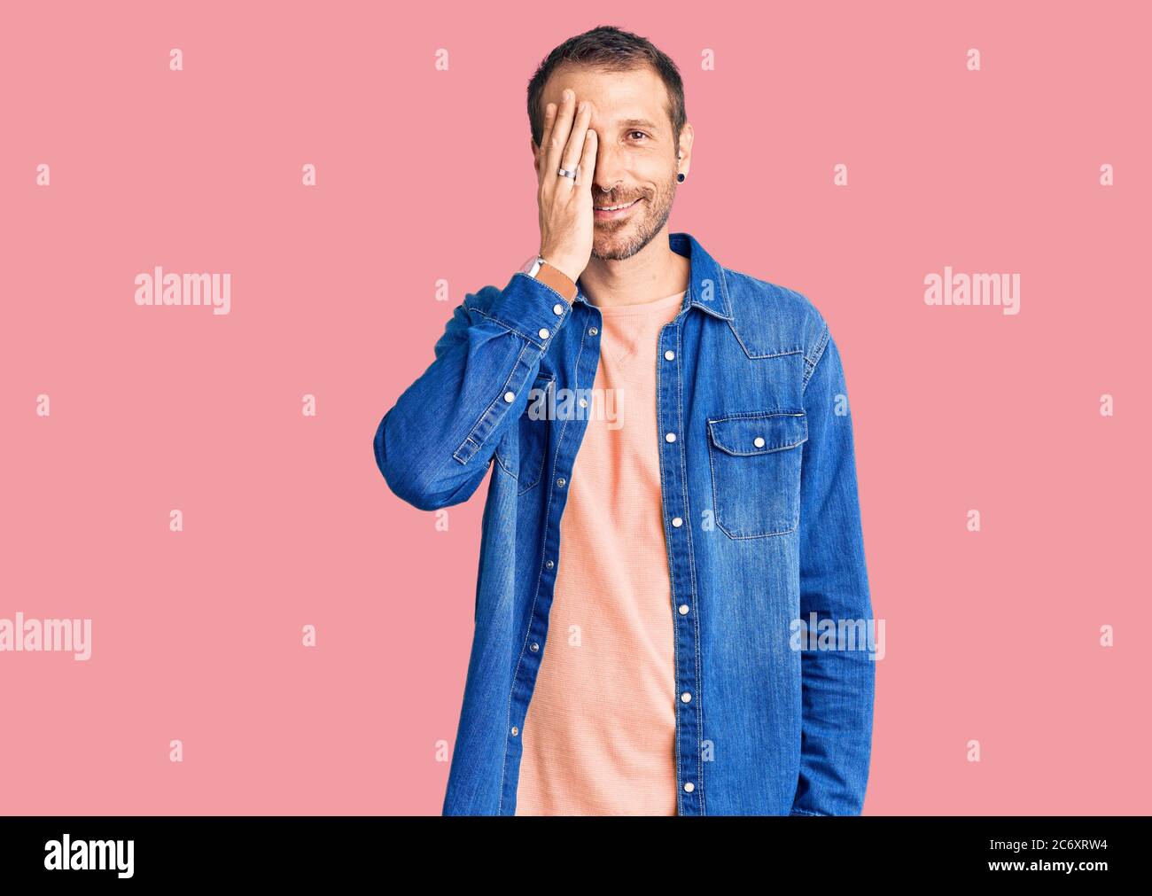 Young handsome man wearing casual clothes covering one eye with hand ...