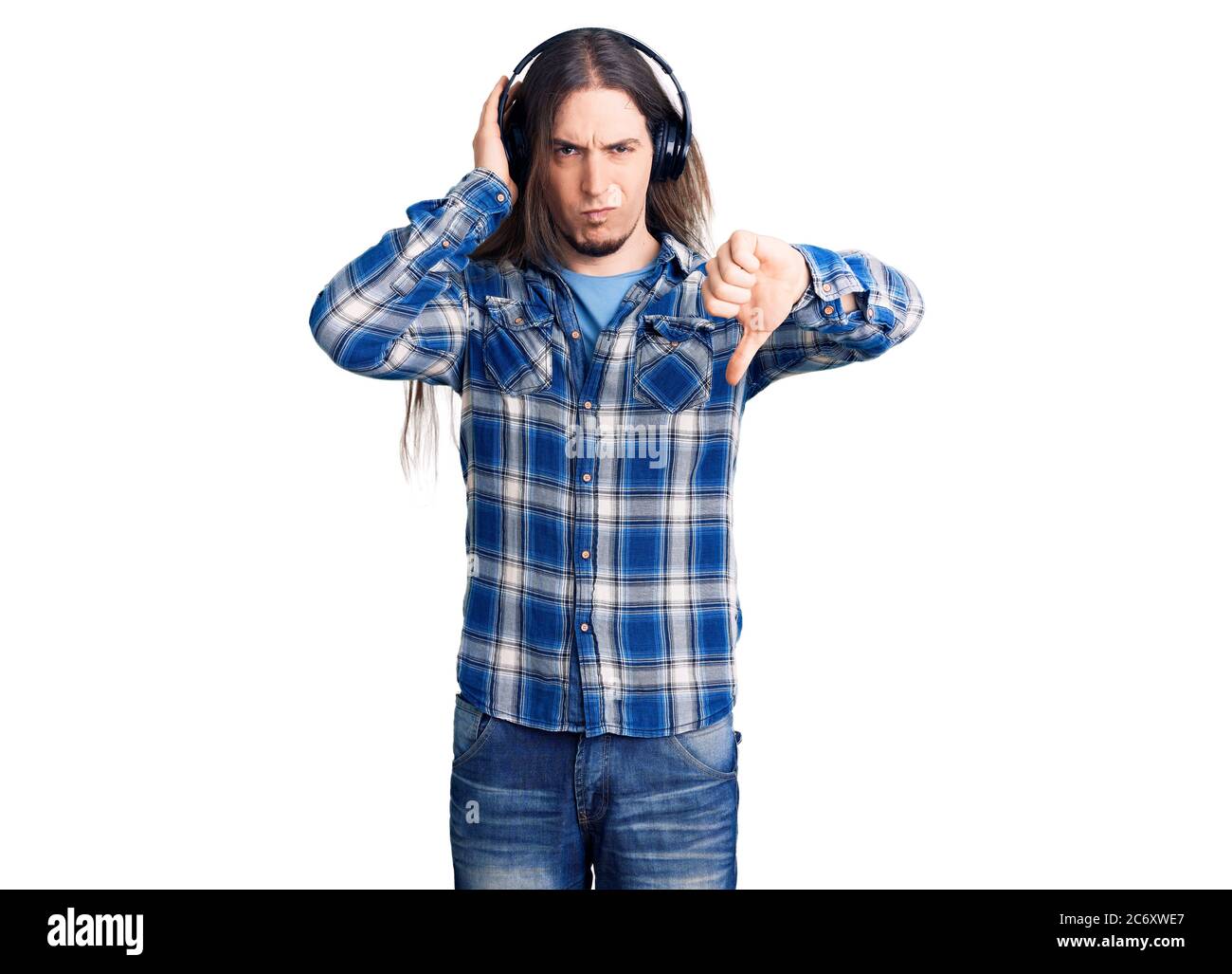 Young adult man with long hair listening to music using headphones with ...