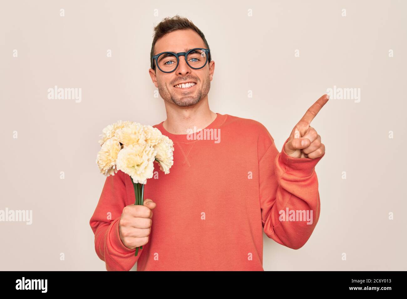 Young handsome man with blue eyes holding bouquet of flowers over white ...