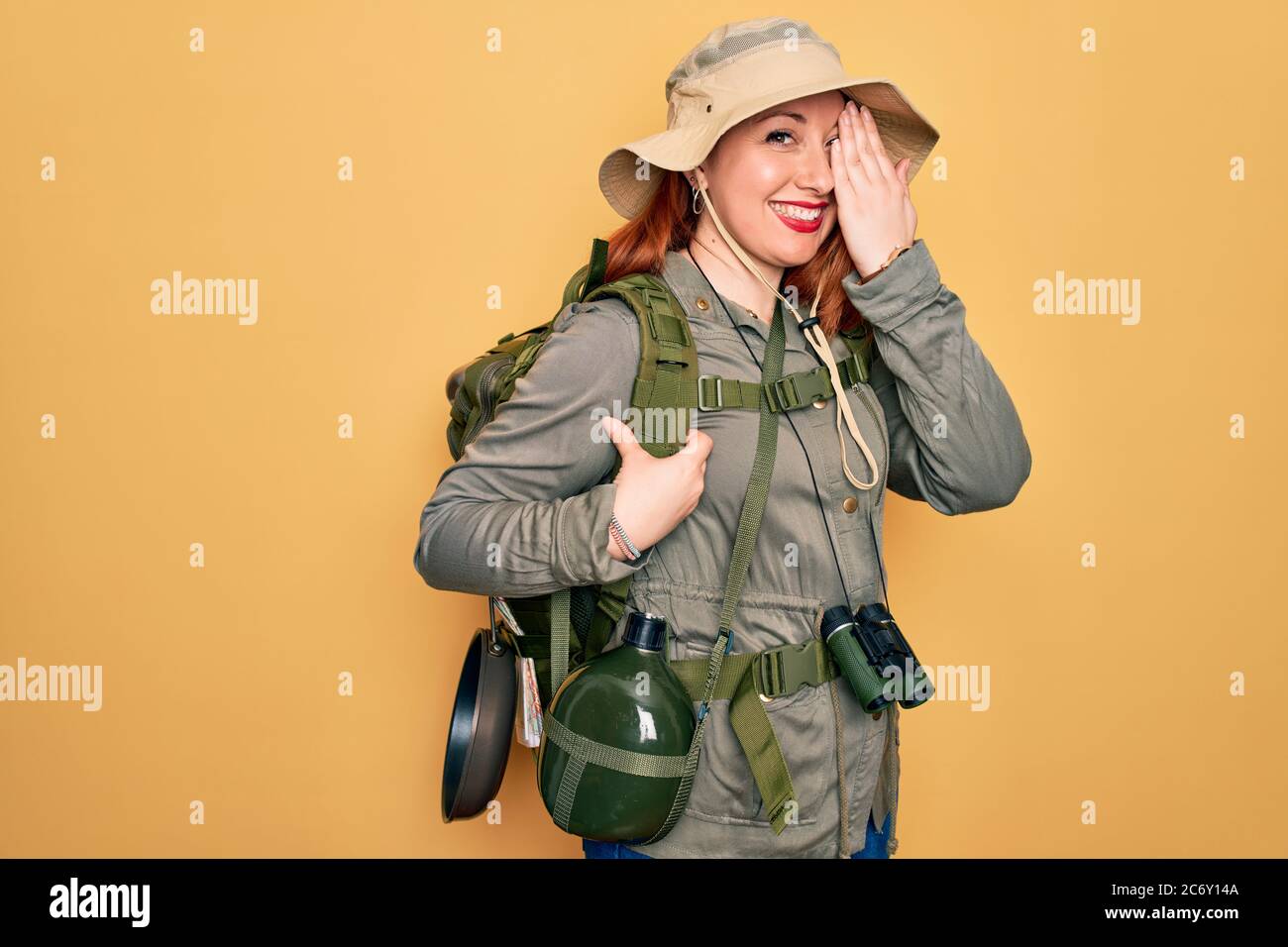 Young redhead backpacker woman hiking wearing backpack and hat over ...