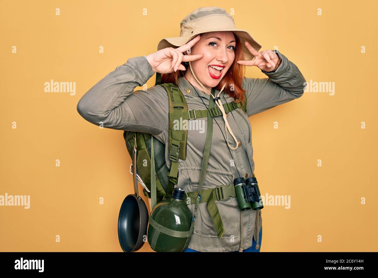 Young redhead backpacker woman hiking wearing backpack and hat over ...