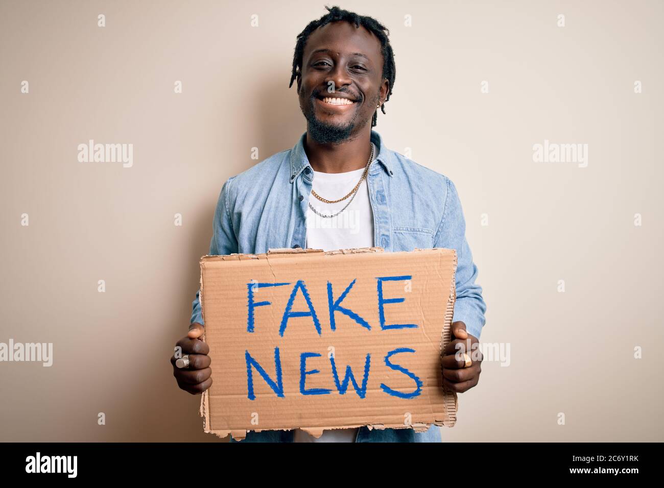 Young african american man holding banner with fake news message over ...