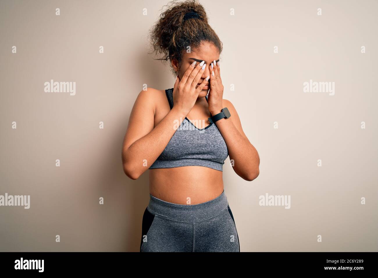 Young african american sportswoman doing sport wearing sportswear over white background rubbing eyes for fatigue and headache, sleepy and tired expres Stock Photo