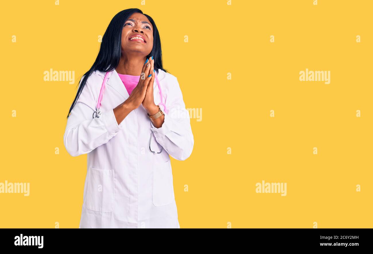 Young african american woman wearing doctor stethoscope begging and praying with hands together with hope expression on face very emotional and worrie Stock Photo
