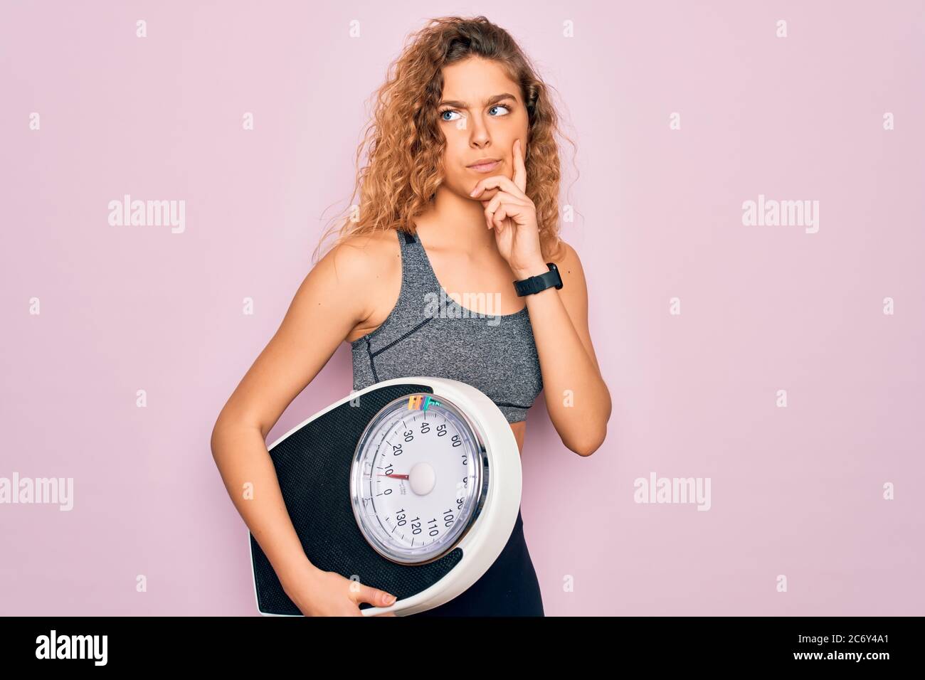 Young beautiful slim sporty woman with blue eyes controlling weight ...