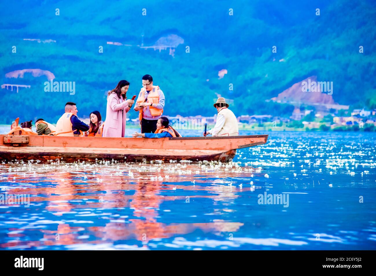 Visitors on a boat enjoy flower blossom of ottelia acuminata, a plant species endemic to Southern China at Lugu Lake in between Ninglang county of Yun Stock Photo