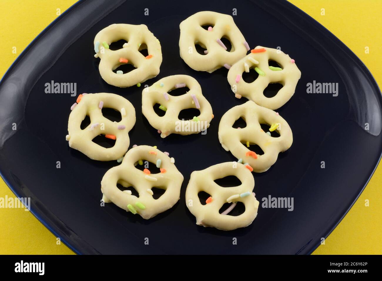 Festive pretzels dipped in white chocolate with sprinkles on blue snack