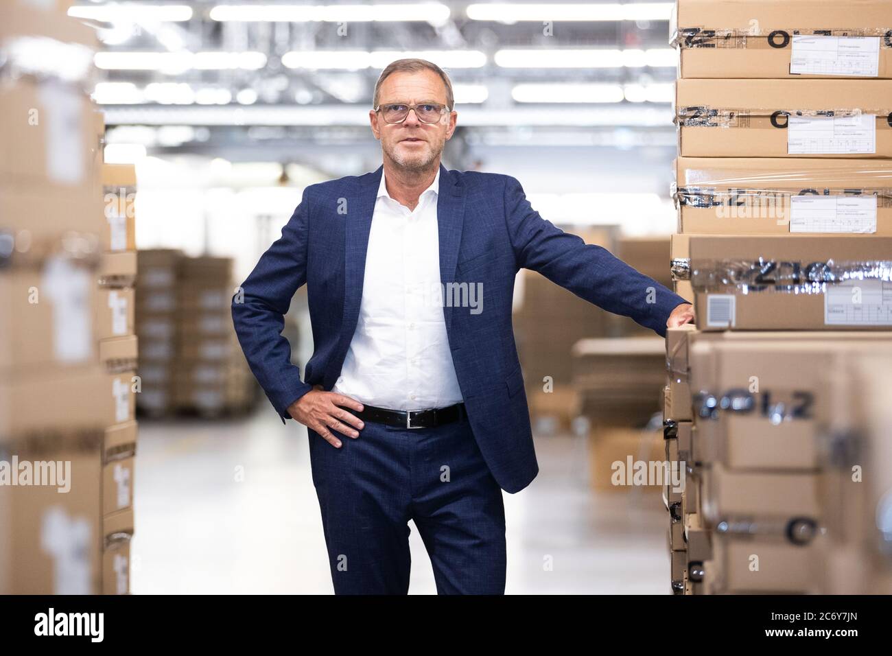 Bietigheim Bissingen, Germany. 09th July, 2020. Mark Bezner, managing  director of Olymp Bezner KG, stands next to cartons in the warehouse. The  suppliers, some of whom Olymp has been working with for