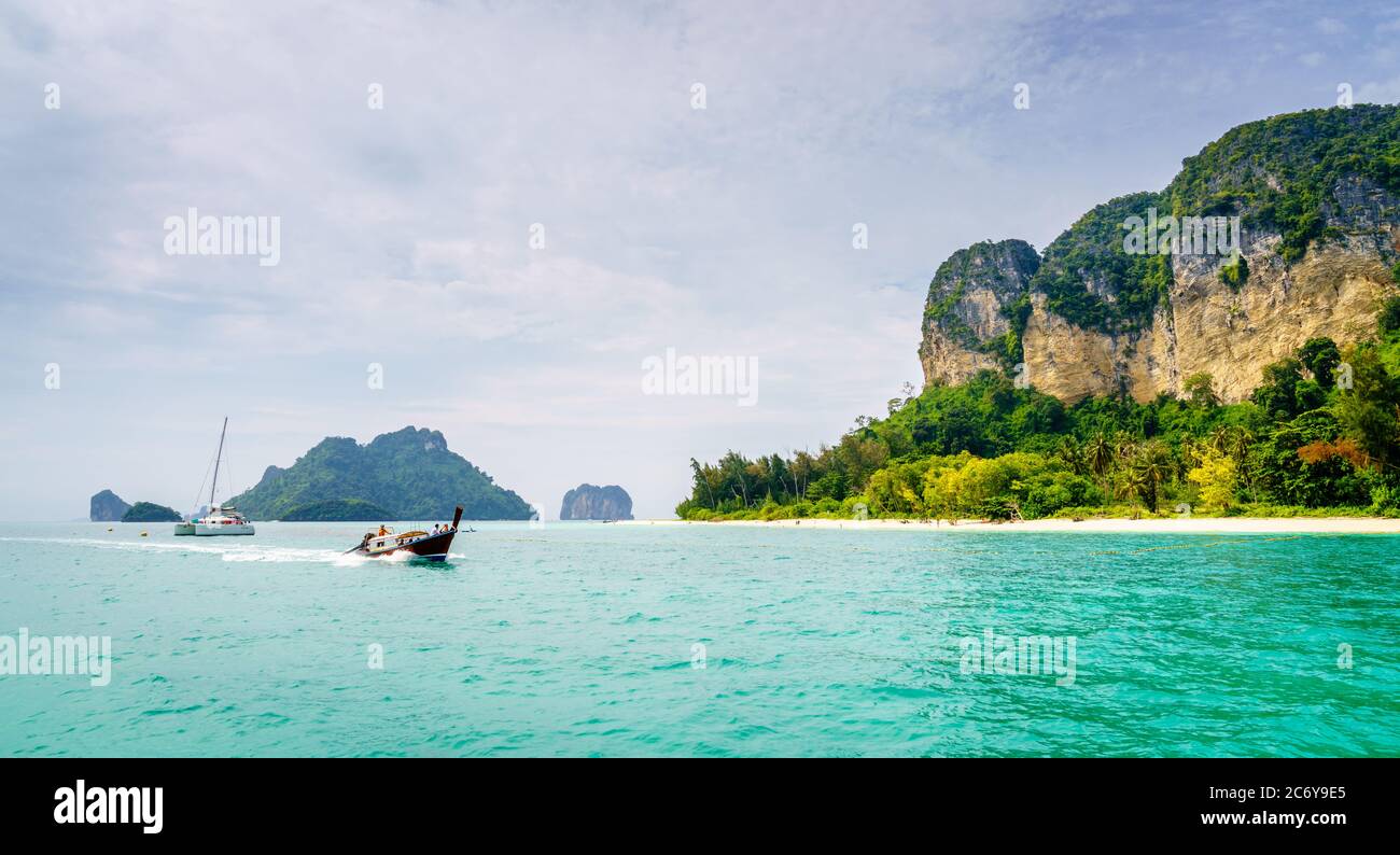 Thai long tail boat speeding past a beach at an island off Krabi coast in the Andaman Sea, Thailand Stock Photo