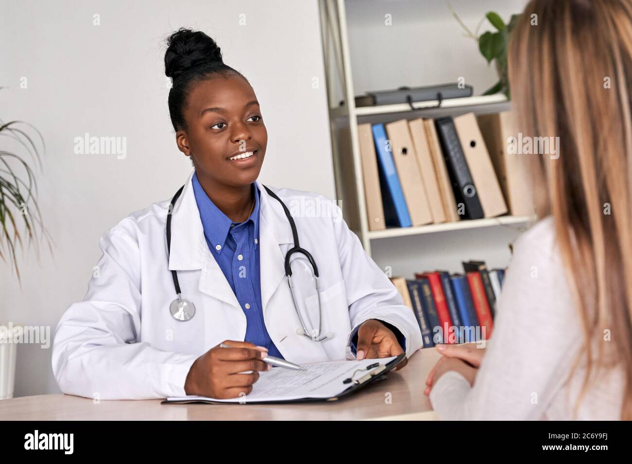 African doctor physician consulting caucasian woman patient at medical visit. Stock Photo