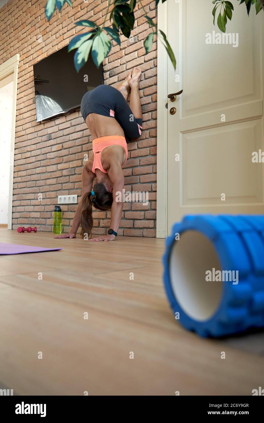 Fit yogi woman wear sportswear doing handstand exercise at home at the wall. Stock Photo