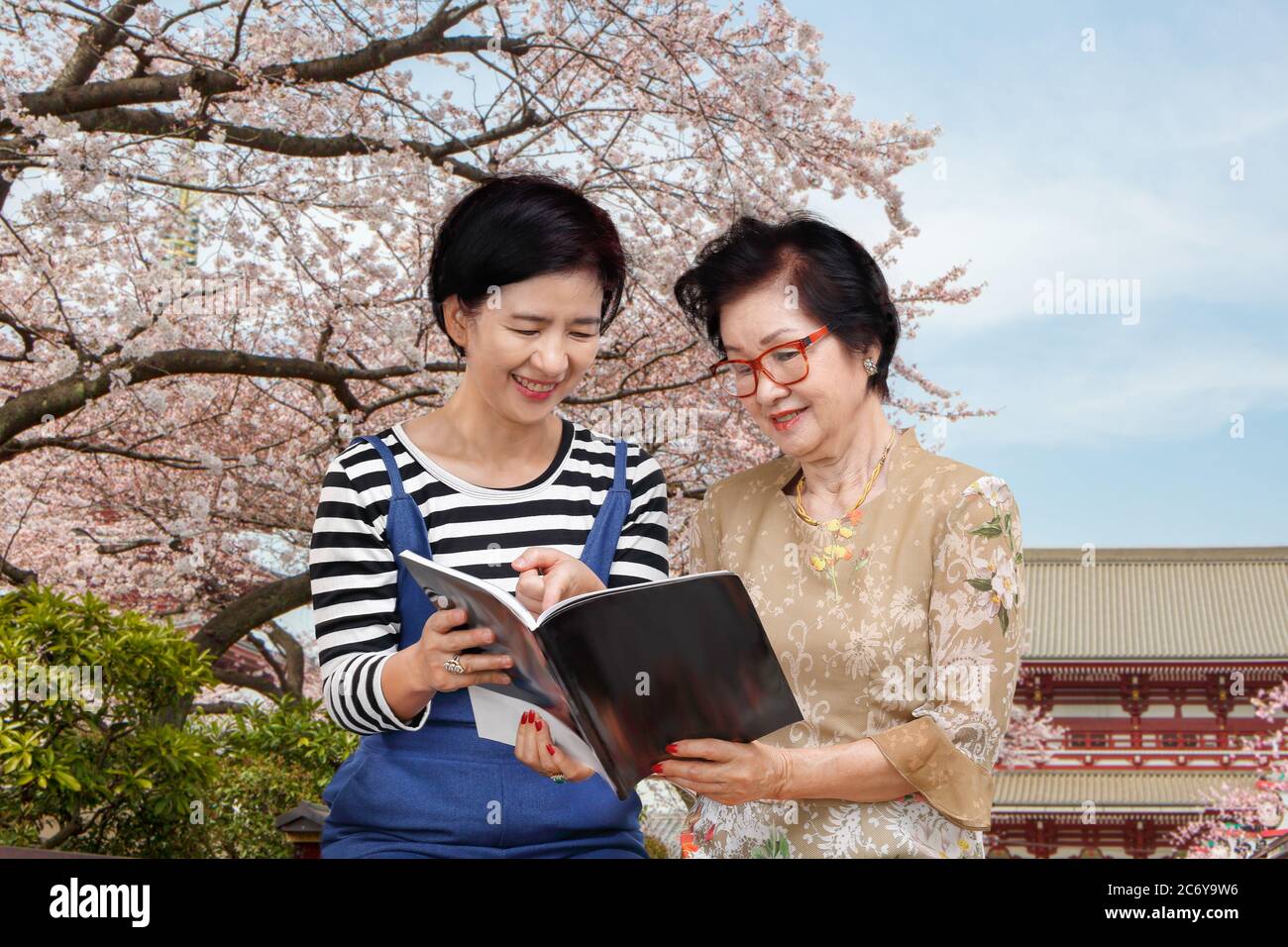 Senior woman reading a travel guidebook with her daughter Stock Photo