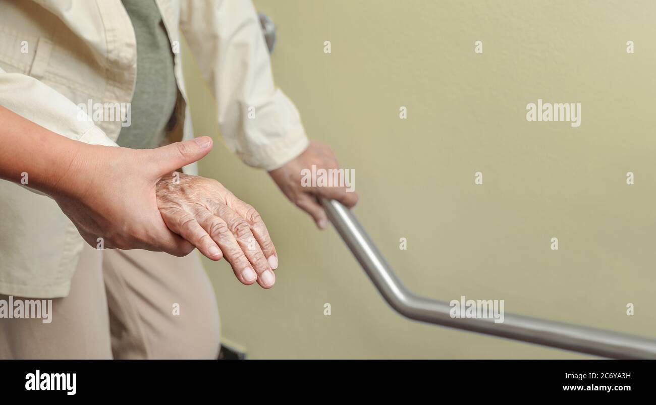 Elderly woman holding on handrail with caregiver Stock Photo