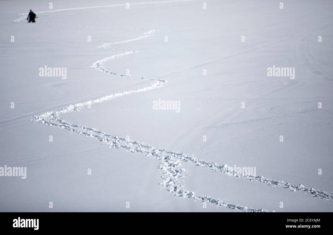 A male fisherman , far away , wading on deep snow on lake ice at Winter , Finland Stock Photo