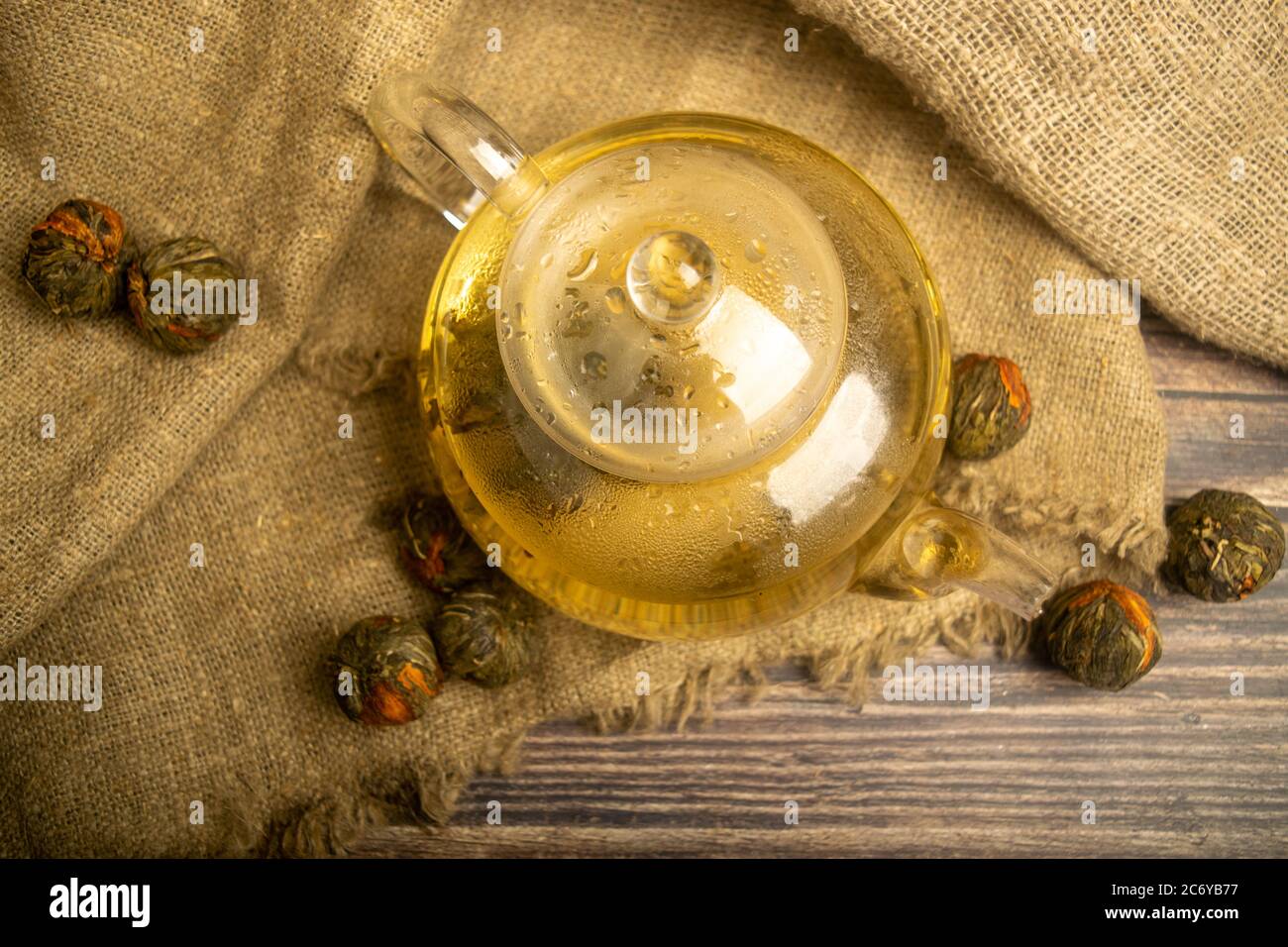 Flower tea brewed in a glass teapot on a background of homespun fabric with a rough texture. Close up Stock Photo