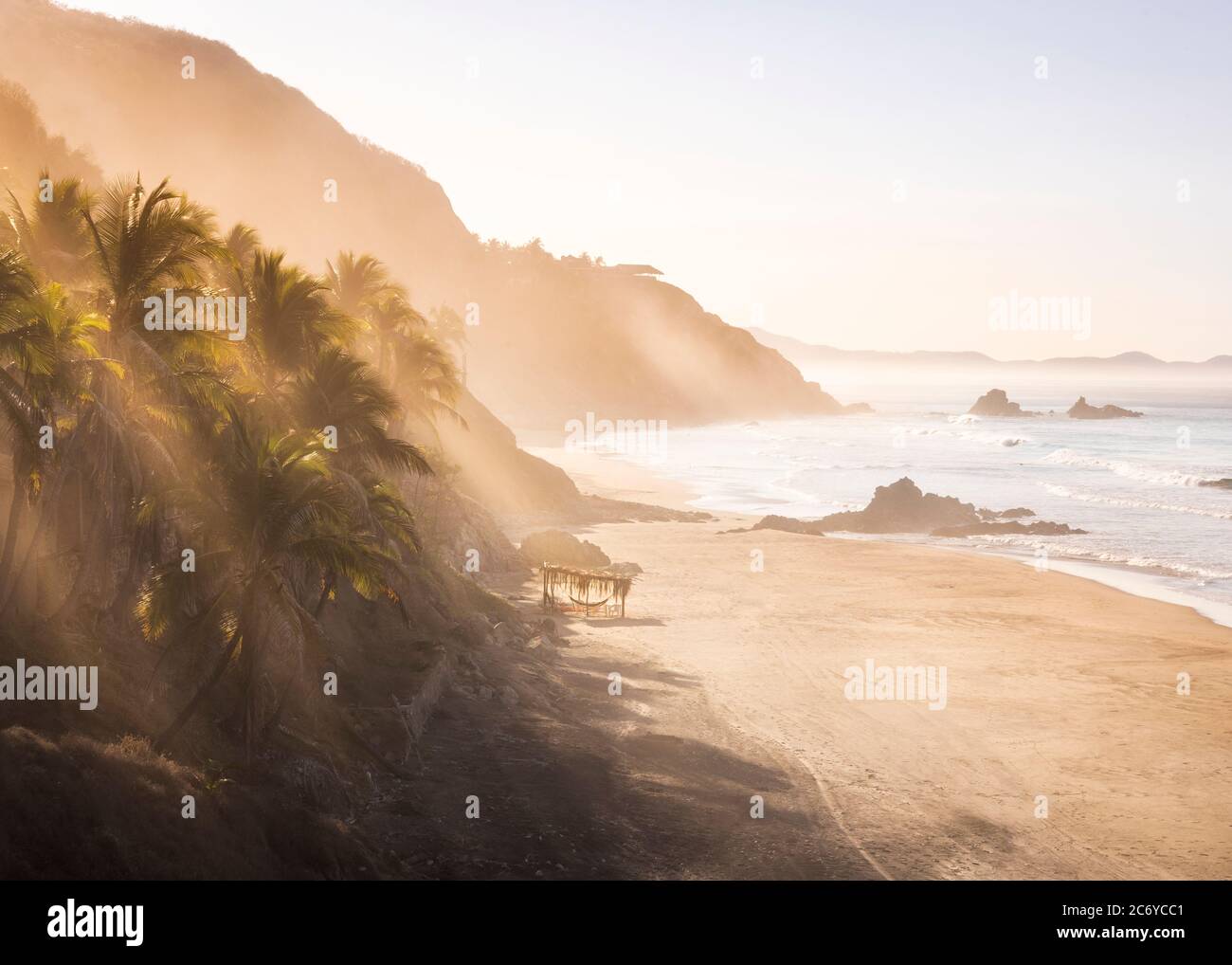Early morning sun filters through palms near El Calvario beach on the Costa Grande of Guerrero, Mexico. Stock Photo
