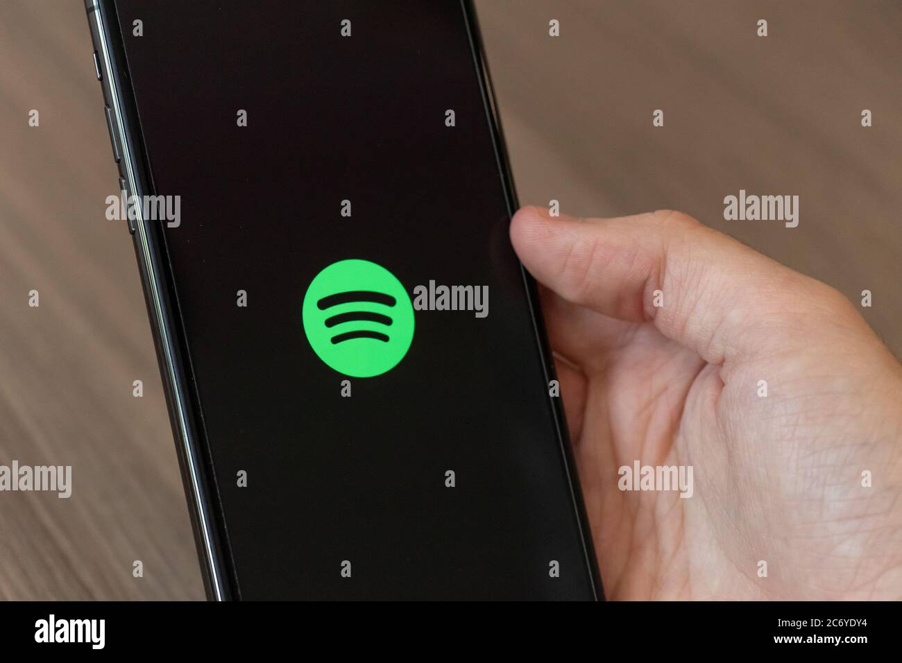 Person using a cellphone with the Spotify music streaming and media service logo on-screen. Stock Photo