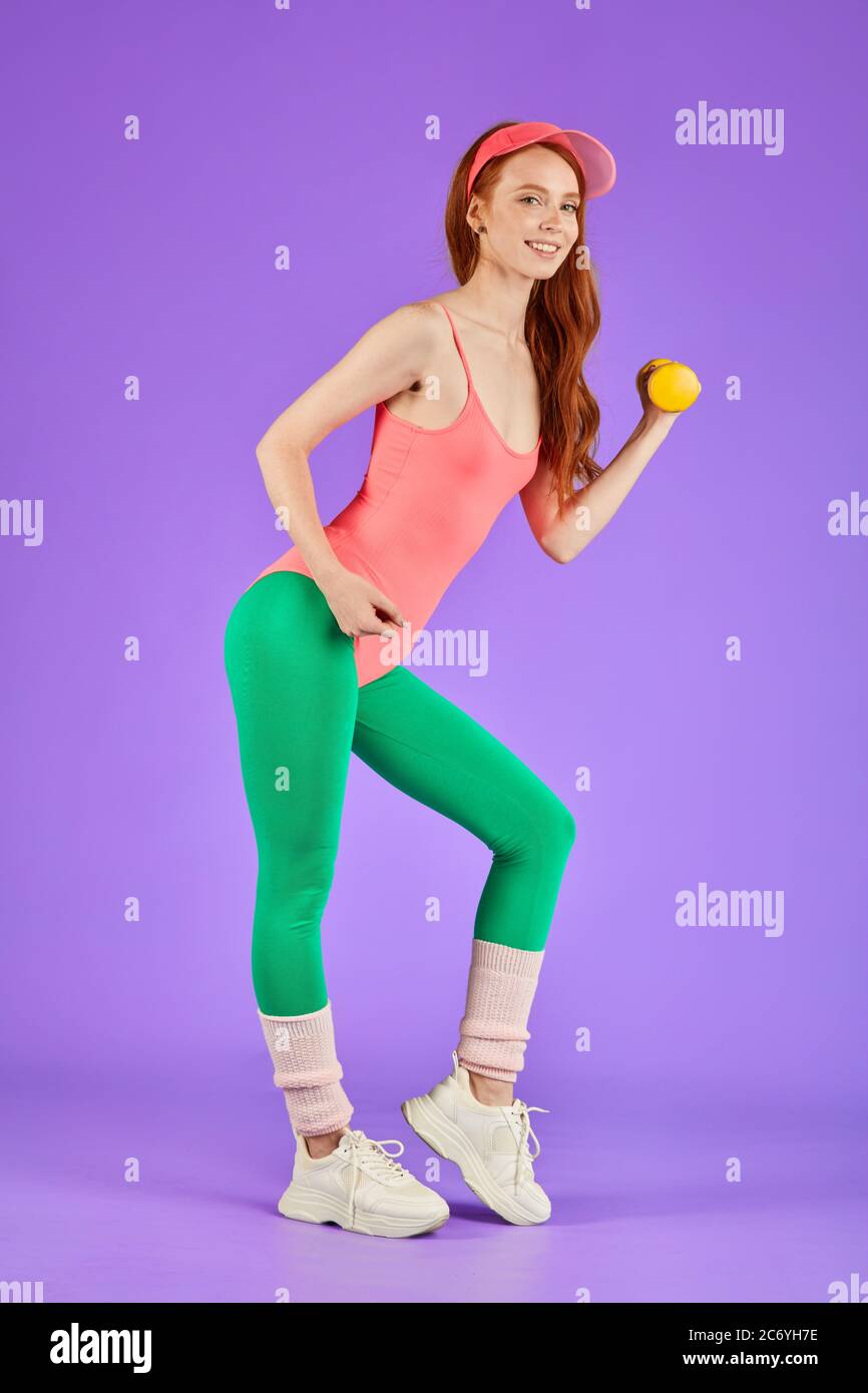 female blogger posing at personal photoshoot for her account, lifts small  weights, stands with yellow dumbbell, dressed in 80s style aerobics clothes  Stock Photo - Alamy