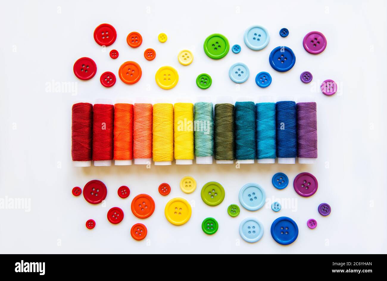 Spools of thread and buttons on the colors of the rainbow on a white ...