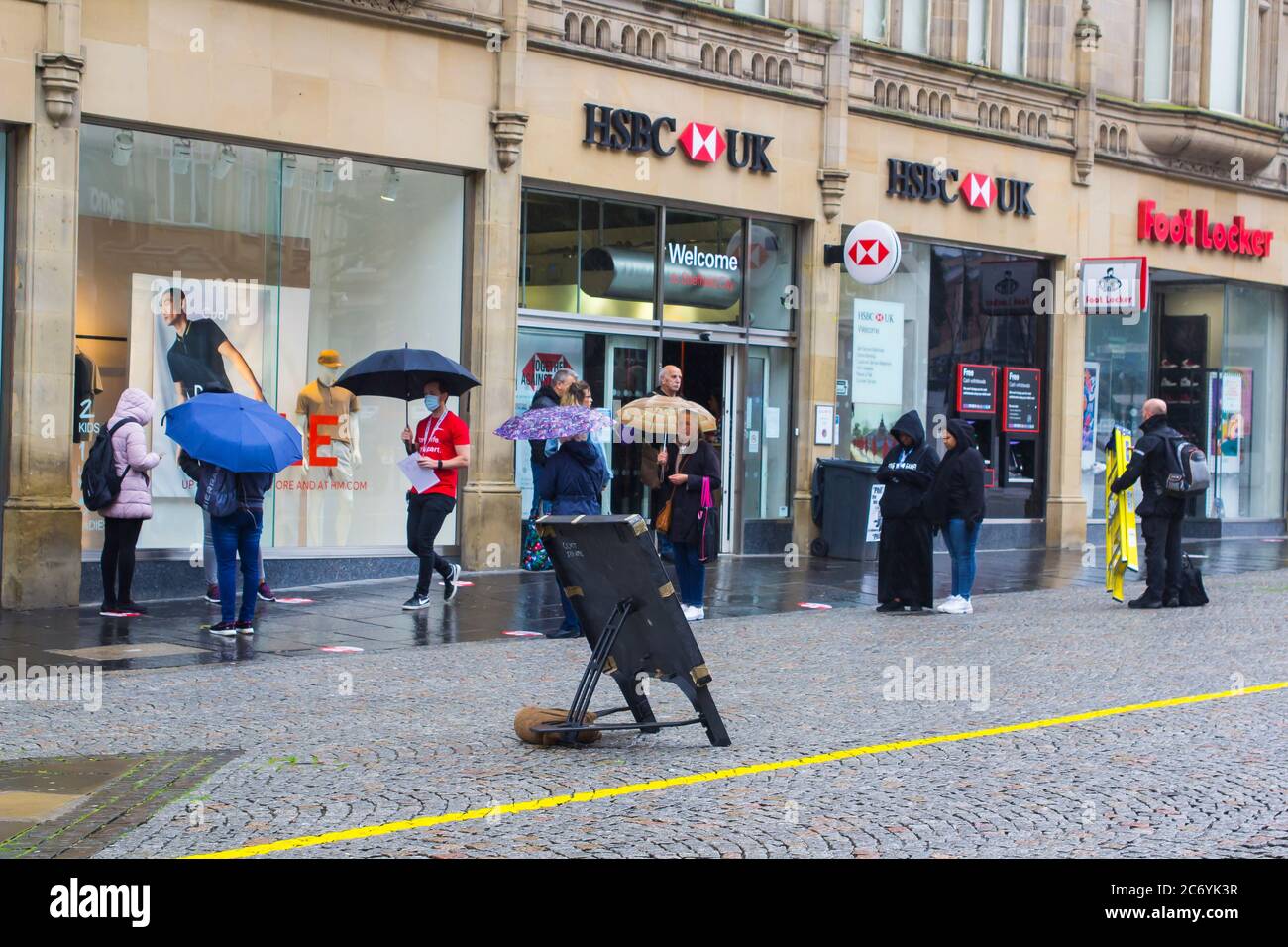 8 July 2020 Customers maintain social distancing as they queue in the rain outside the HSBC Bank branch in Fargate Sheffield City centre England Stock Photo