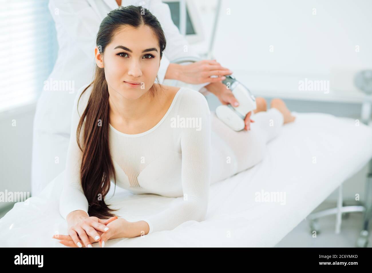 Portrait of brunette woman dressed in white LPG slimming bodysuit