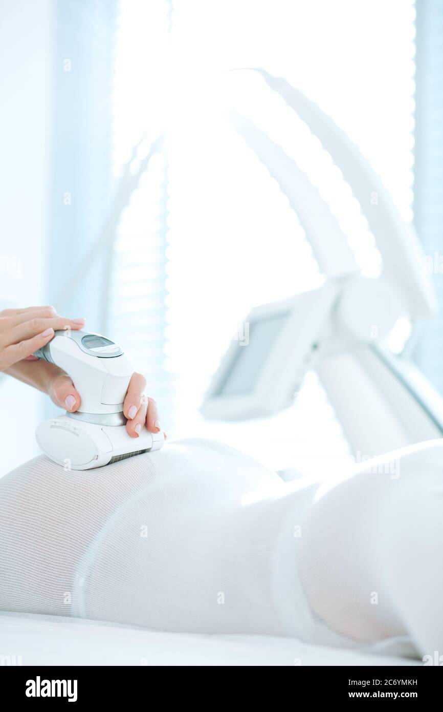 close up of female back and buttocks, in white LPG slimming bodysuit