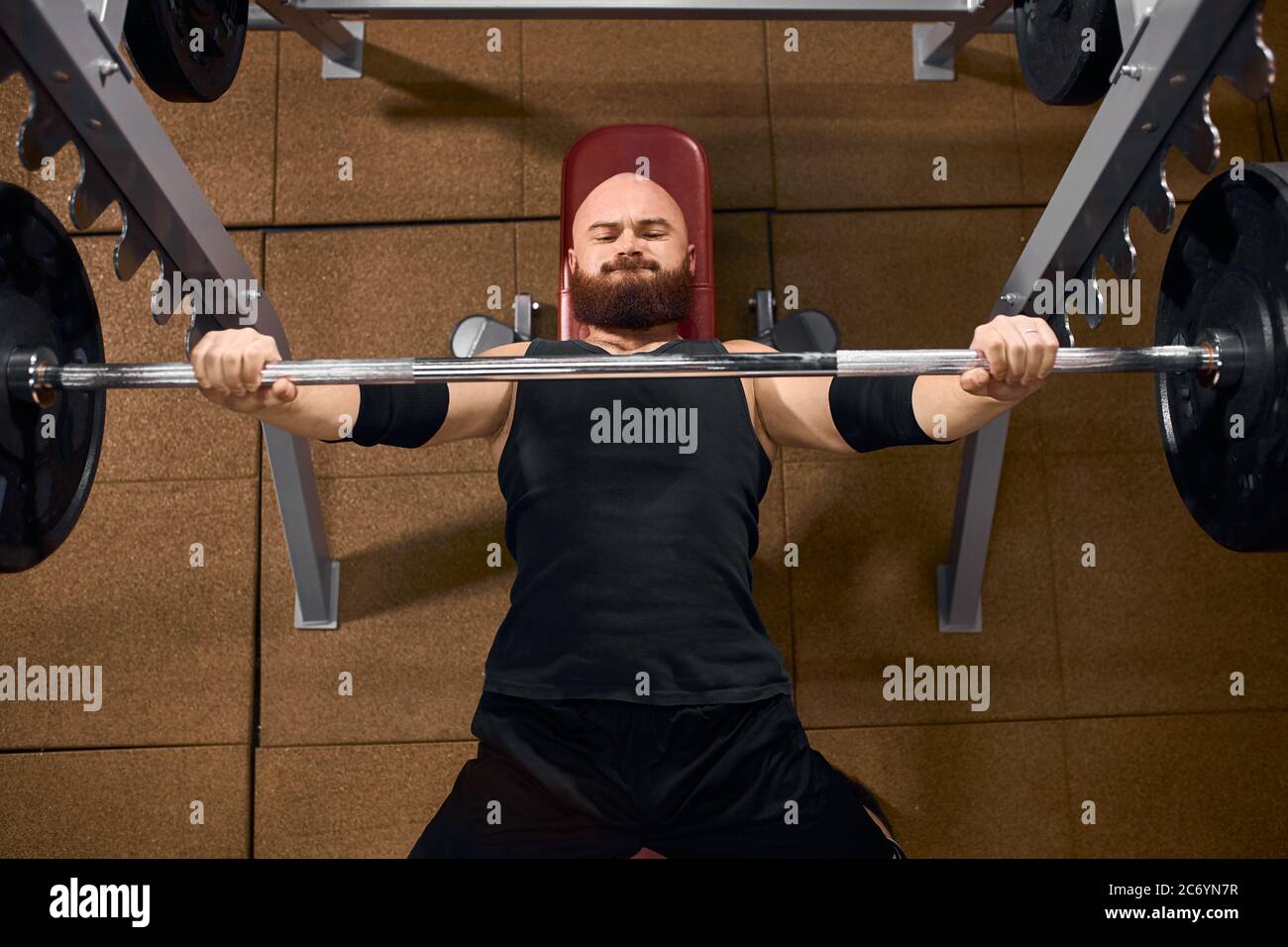 Strong powerful man dressed in black shirt and shorts, having stylish arm  bands, lifting heavy barbell, attempting bench press, looking tired,  express Stock Photo - Alamy