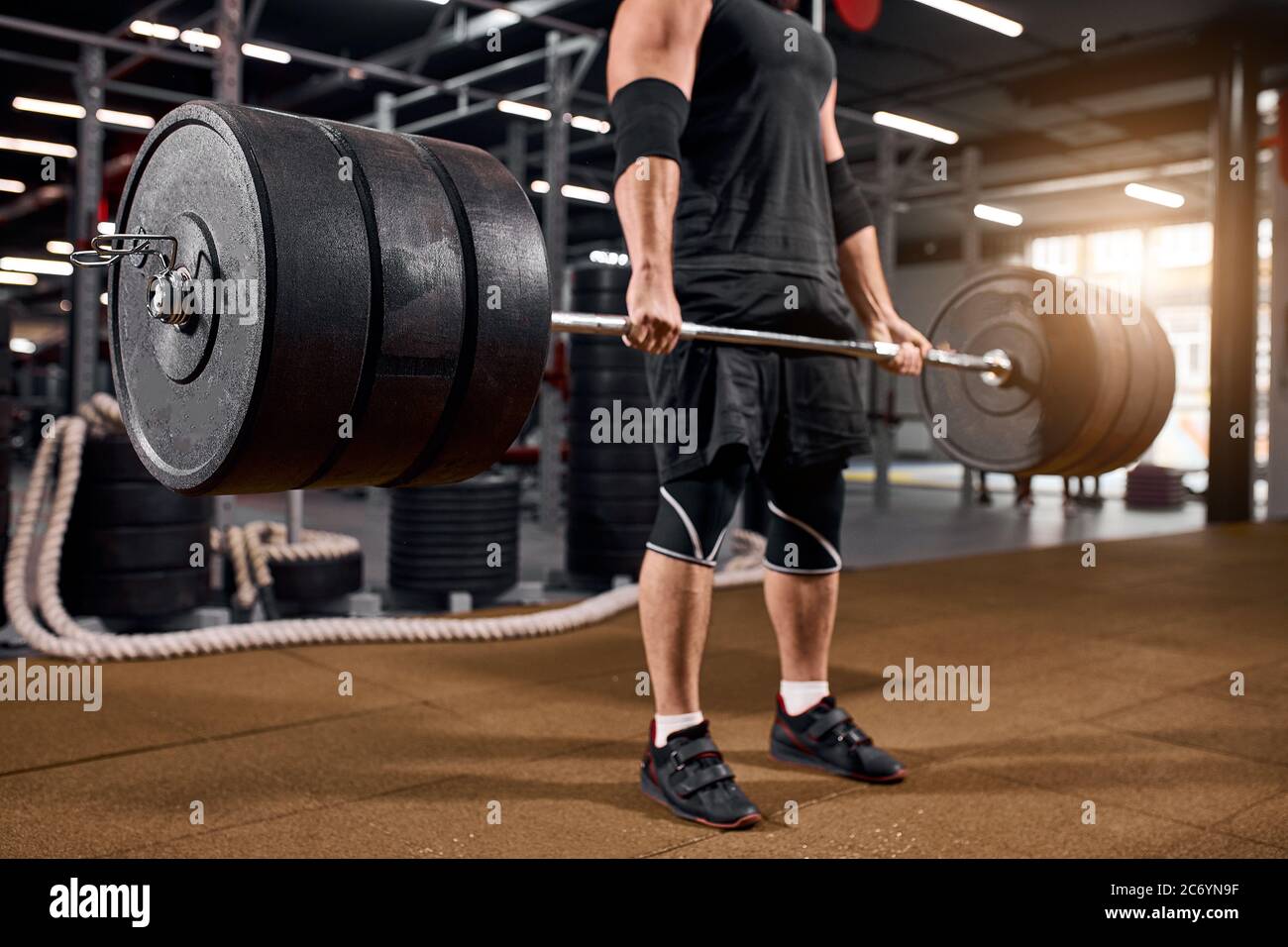 Close view of weightlifter hands standing on brown floor, wearing black sneakers and white socks